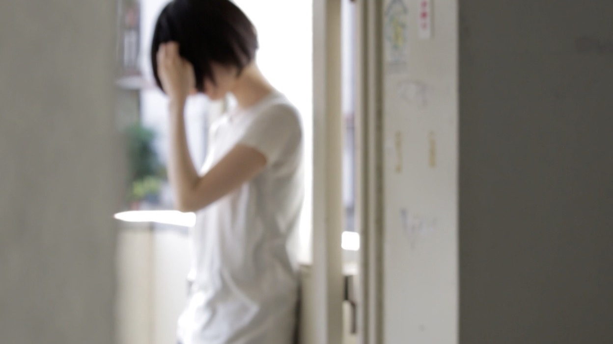 窓辺に立つ白いTシャツの人