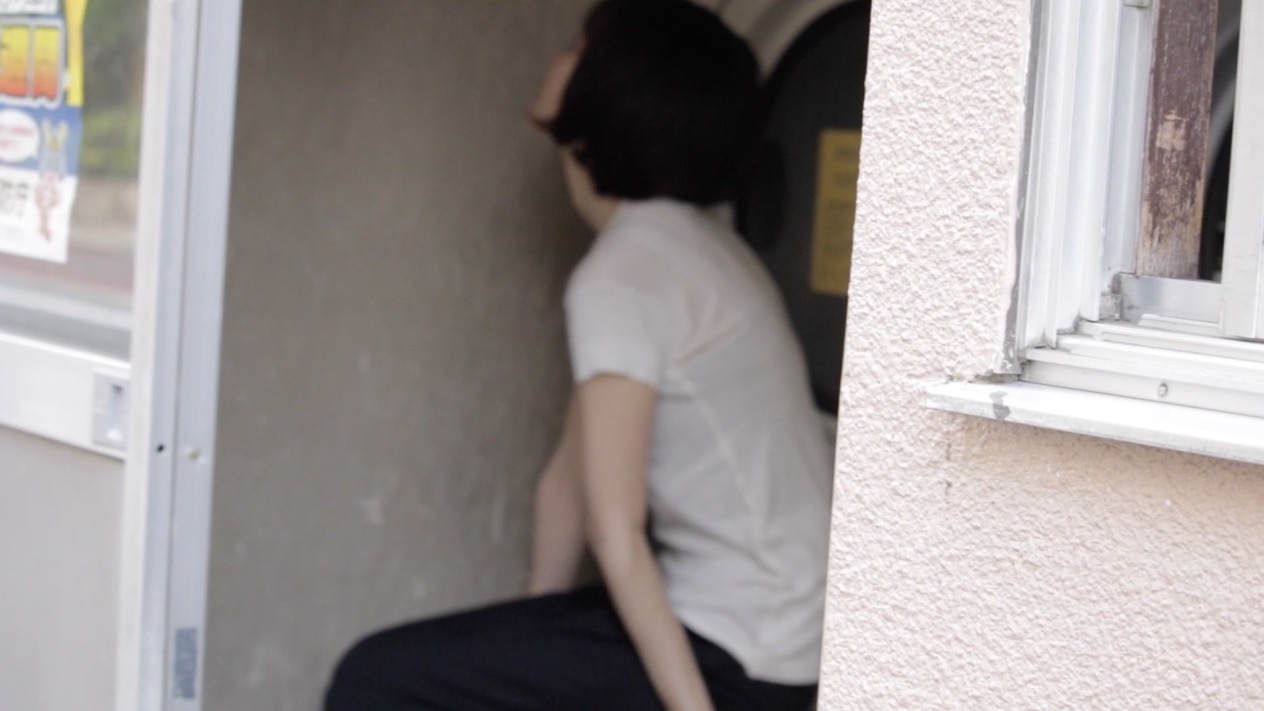 コインランドリーの隅で壁にもたれて座る人